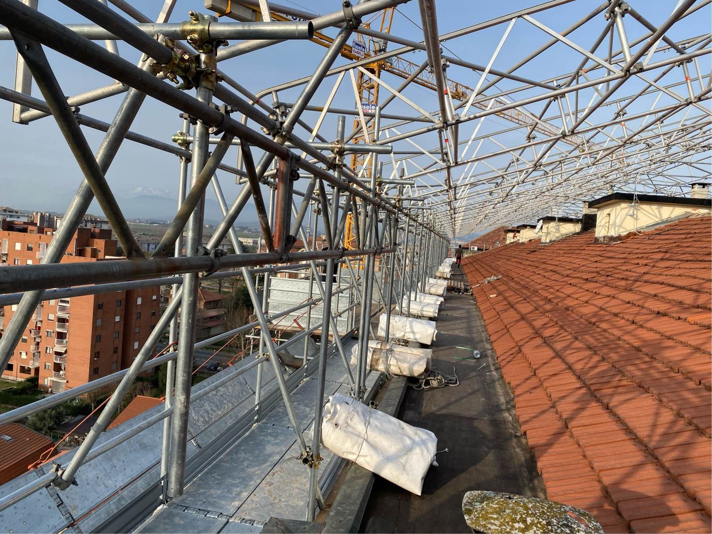 Ponteggio montato lungo la falda di un tetto in coppi durante i lavori di rifacimento